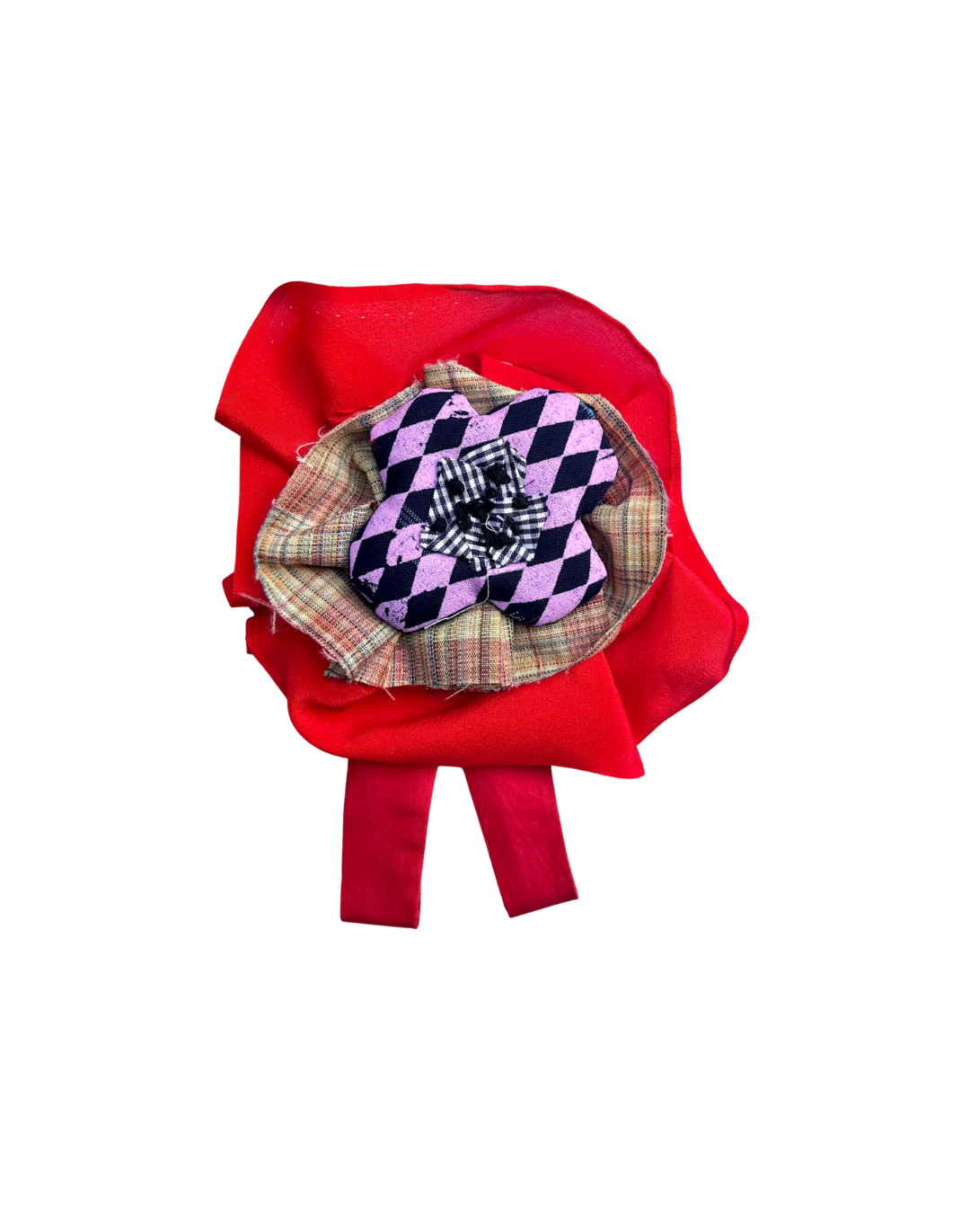 A red fabric flower accessory with a layered center featuring a purple and navy checkered fabric flower, a light pink and beige plaid fabric flower, and a small white embroidered monogram on a black background.