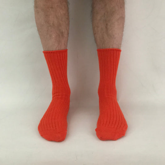 Orange socks worn by a person on a light gray background