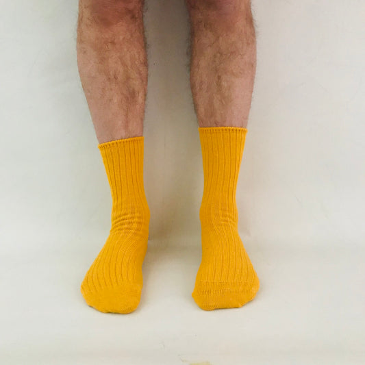 Yellow socks worn by a person on a plain background