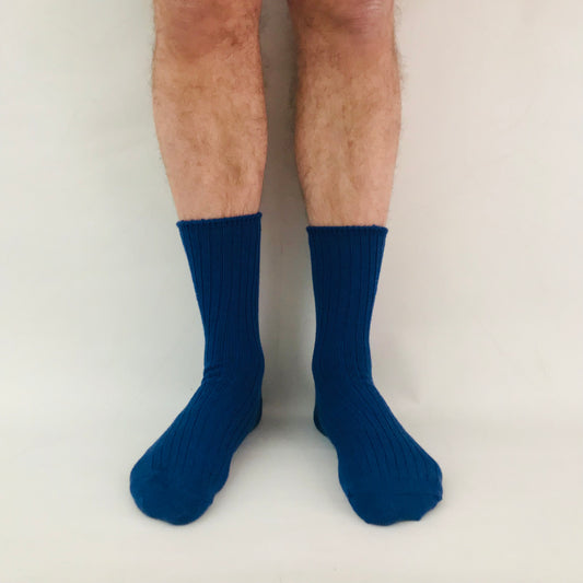 Blue socks worn by a person on a plain background