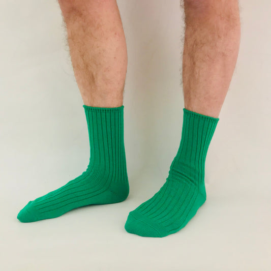 Green socks worn by a person on a plain background