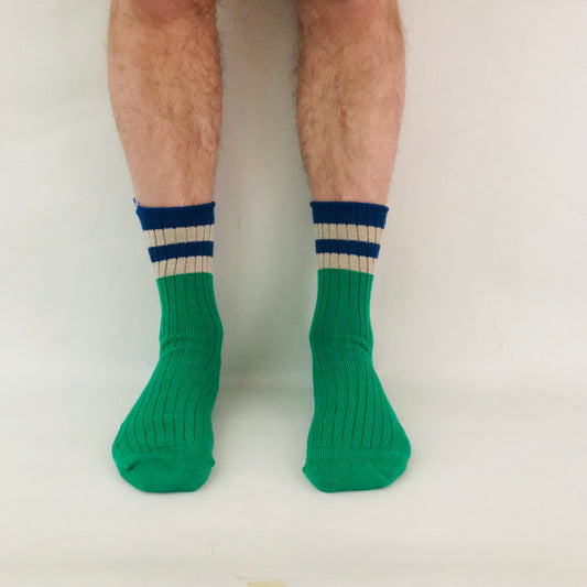 Green socks with blue and white stripes worn by a person on a plain background